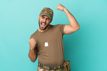 Military with dog tag over isolated on blue background celebrating a victory
