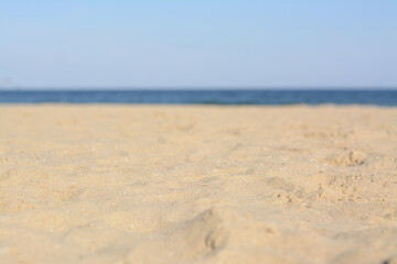 Fototapeta na wymiar Blurred view of sandy beach near sea on sunny day