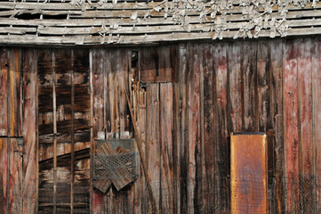 Broken down weathered and abandoned wooden barn with missing wooden shingles 