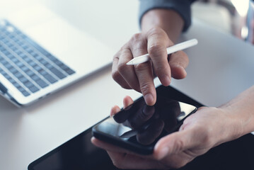 Close up of business man hand holding and using mobile smart phone with stylus pen, digital tablet...