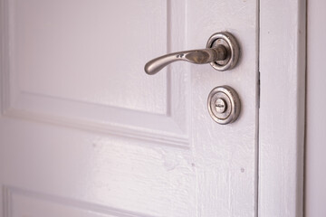 Detail of a closed old wooden door with a lock handle and a white background. Metal handle and lock on the front door