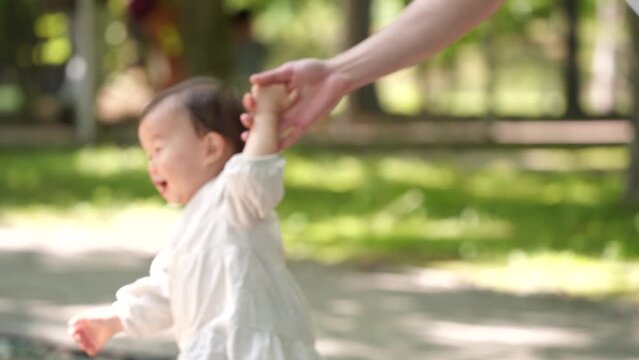 1歳4ヶ月の赤ちゃんと手を繋いで歩く父親