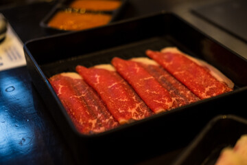 Thinly sliced meat in the black tray.