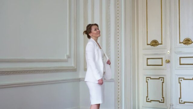 an attractive woman in a white business suit in a classic white interior. 