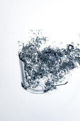 transparent glass dropped into the water on a white background