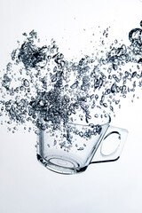 transparent glass dropped into the water on a white background