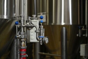 Taps in equipment with a manometer on a blurred background of a beer production