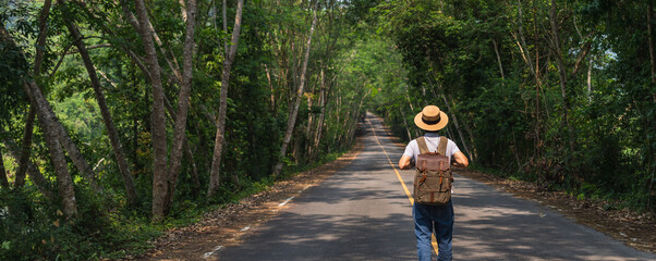 Asian man travel and walking on the road in forest landscape background.Concept of travel in spring...