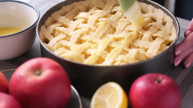Apple pie cake preparation series - Woman brushing pie with beaten eggs before to put them in oven
