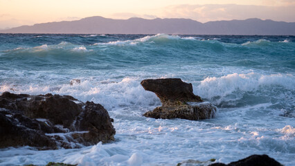 Fototapeta na wymiar Sea ​​wave at sunset hitting rock on the beach.