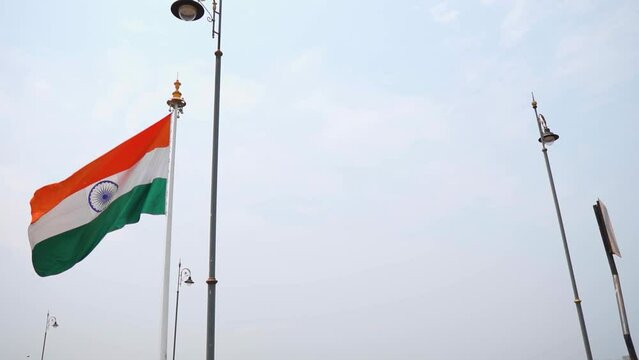 Slow motion shot of Indian flag waving in the wind on the side of the road as seen after crossing the Atal setu bridge at Goa in India. Indian flag as seen from moving vehicle on a bridge.