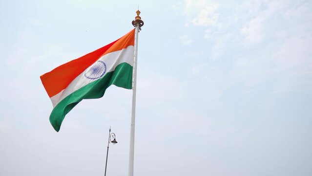 Slow motion shot of Indian flag waving in the wind on the side of the road as seen after crossing the Atal setu bridge at Goa in India. Indian flag as seen from moving vehicle on a bridge.