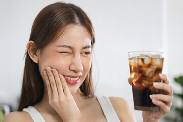 Person touch her cheek feeling sensitive teeth after drink cold soda