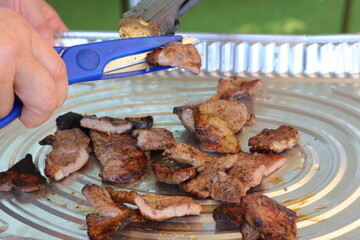 BBQの肉をアルミホイル皿の上でハサミでカットする。キャンプ、野外パーティ、アウトドアイメージ。