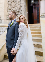 Fototapeta premium Beautiful caucasian newlywed couple posing on the background of an ancient house. Fine art wedding