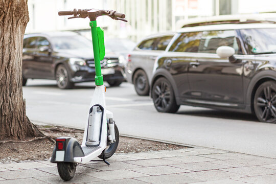 Electric Ride Sharing Scooter. Dockless Scooter For Rent On Street On Background Of Cars. Urban Bicycle Transport