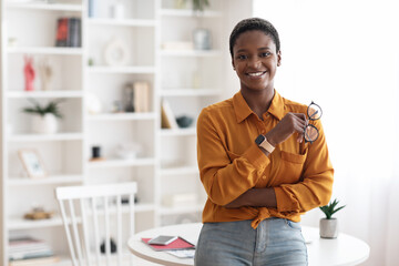 Happy successful young black woman posing at office