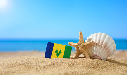 Fototapeta na wymiar Tropical beach with seashells and Saint Vincent and the Grenadines flag. The concept of a paradise vacation on the beaches of Saint Vincent and the Grenadines.