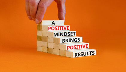 Positive mindset symbol. Wood blocks with words A positive mindset brings positive results. Beautiful orange background Businessman hand. Business motivational positive mindset concept. Copy space.