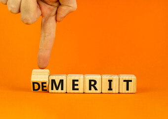 Demerit or merit symbol. Businessman turns wooden cubes and changes the concept word Demerit to Merit. Beautiful orange table orange background. Business and demerit or merit concept. Copy space.