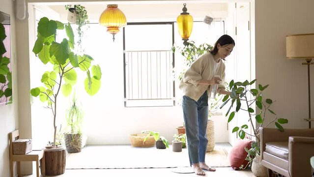 部屋の観葉植物に水をあげる女性