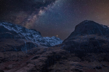 Majestic vibrant Milky Way composite image over landscape of snowcapped mountains in Scottish...