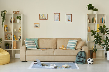 Interior of cozy living room with kids stuff and ship pictures above sofa, house design concept