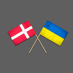 Flags of Denmark and Ukraine, on wooden sticks. Isolated on a gray background. International political relations. Commonwealth. Support. Political Economic
