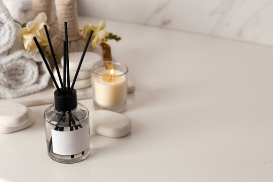 Aromatic reed air freshener and spa stones on white table, space for text