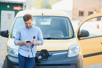 Man charging his electric car at charge station.