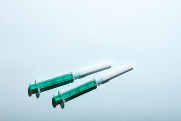 A pair of medical syringes on blue background with free copy paste space for text.