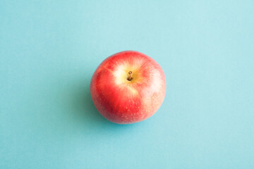 Minimalist image of a red apple on blue background.