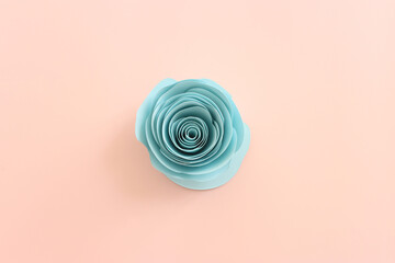 Top view image of colorful paper flowers composition over pastel pink background