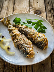 Fish dish - marinated fried herrings on wooden table
