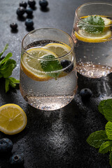 Detox water, infused refreshing drink with lemon and blueberry and mint. Dark moody photo