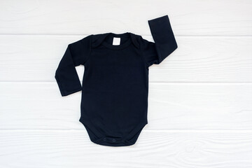 Blank black baby bodysuit long sleeve flatlay mockup on white wood background, copyspace, top view.