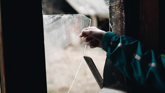 A boy takes a piece of glass out of a frame in an abandoned house. Shooting in close-up