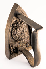 Close up on a old heavy cast iron ironing, isolated on white background. Beautiful vintage object to heat on a stove.