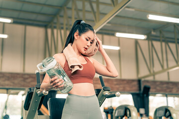 Fitness woman resting from excersise in the gym and drinking water from bottle.