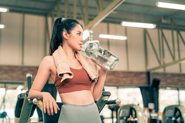 Fitness woman resting from excersise in the gym and drinking water from bottle.