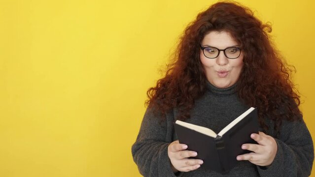 Book lover. Reading passion. Education hobby. Surprised impressed happy smart chubby woman in glasses enjoying story saying wow isolated on yellow copy space background.