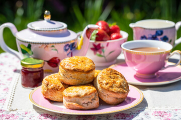 Freshly baked scones with tea served in the garden - obrazy, fototapety, plakaty