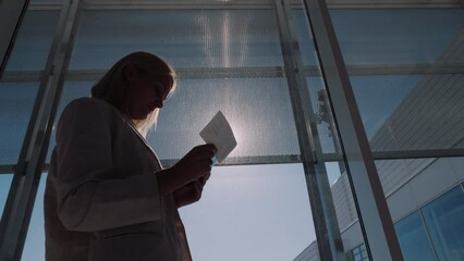 A passenger with a boarding pass in his hands is standing at a large window of the airport terminal