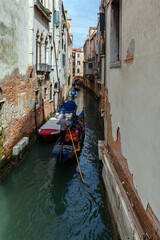 Gondoliers on the canals of Venice carry tourists.