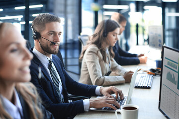 Portrait of call center worker accompanied by his team. Smiling customer support operator at work.