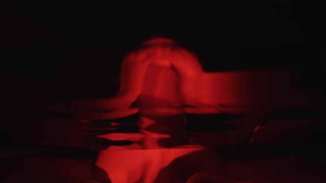 Horror scream. Mental disorder. Panic attack. Creepy silhouette of suffering scared depressed woman in surreal mirror reflection red neon light dark background.