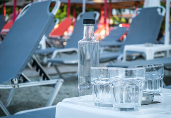 A small quiet tourist place Leptokarya in Greece. Empty glass water bottles, and drinking glasses left on a table in Greece.