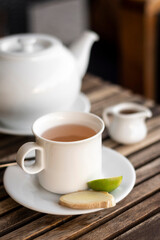ginger and honey tea pot and cup on wooden cafe table outdoors