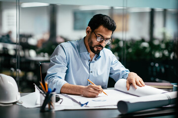 Busy smart attractive millennial arabic male engineer architect with beard in glasses is working at...