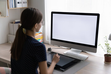 Freelance designer drawing sketch on graphic tablet at desktop big monitor, blank display. Professional girl working on design project at home. Using creative job digital equipment.